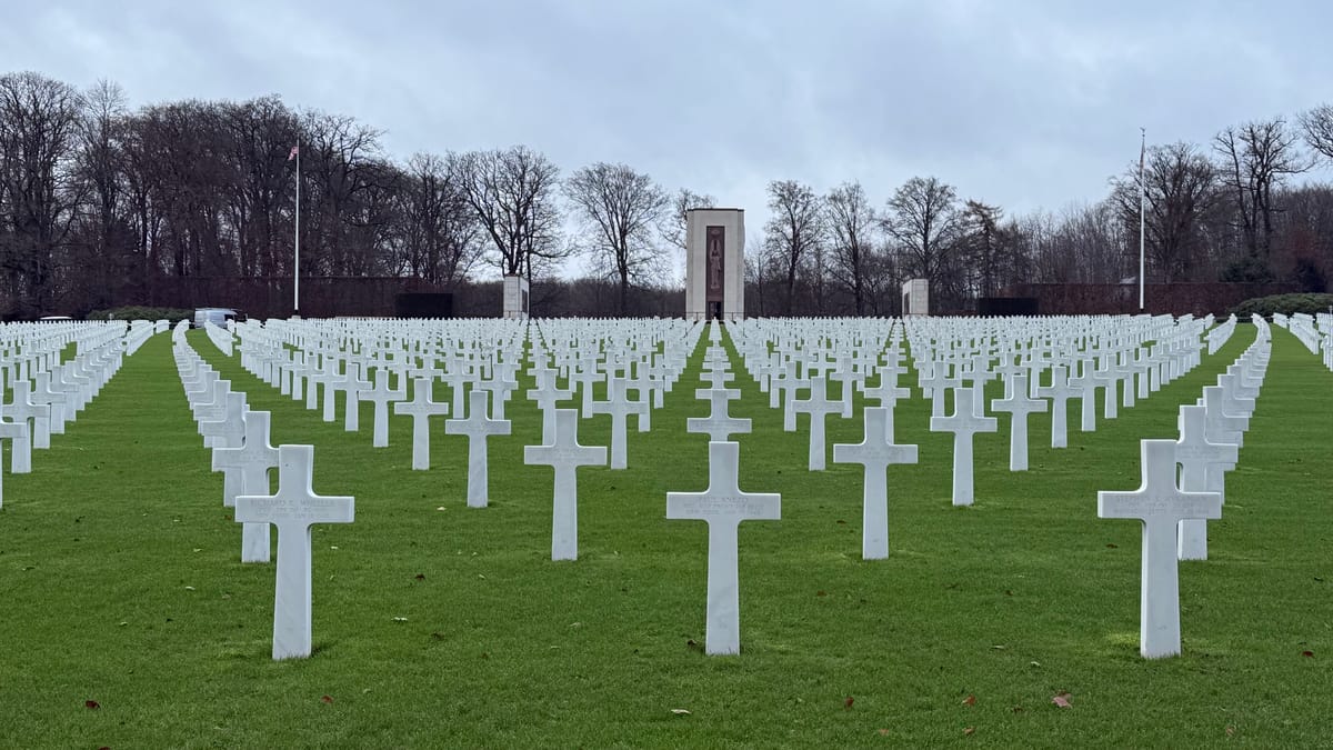 December 9, 2024: The American Cemetery in Luxembourg. Green Grass with white crosses lined up in curving rows with bare trees in the background.